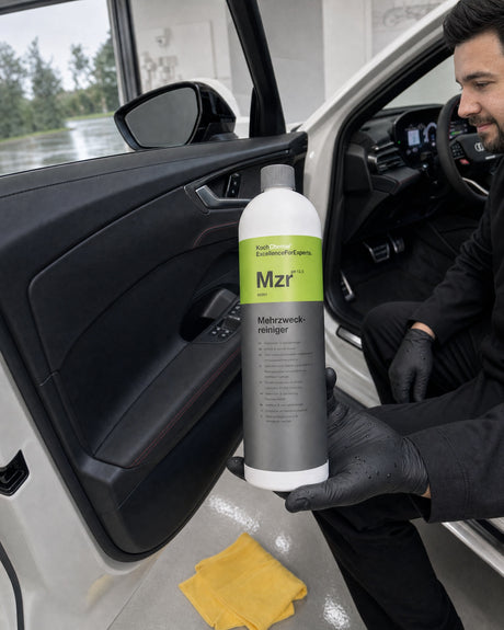 Koch-Chemie multi-purpose cleaner Mzr in Daniel's hand at the open door of the white Audi RS 5, door panel deep black.