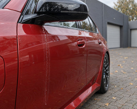 Detailing1 Auto trocknen — Nachlaufwasser aus dem Spiegel zieht Kalkränder über die Tür eines roten BMW M5