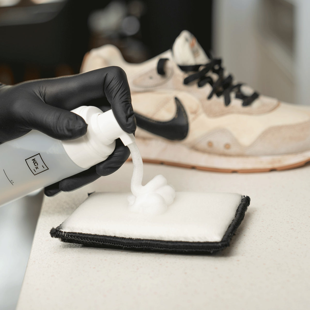 Detailing1 COLOURLOCK Sneaker Cleaner Set — Reinigungsschaum auf dem Pad, dahinter der verschmutzte Sneaker